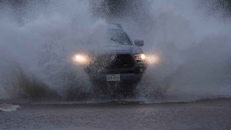 Un auto circula por una carretera anegada debido a las intensas lluvias caídas en la zona, en...