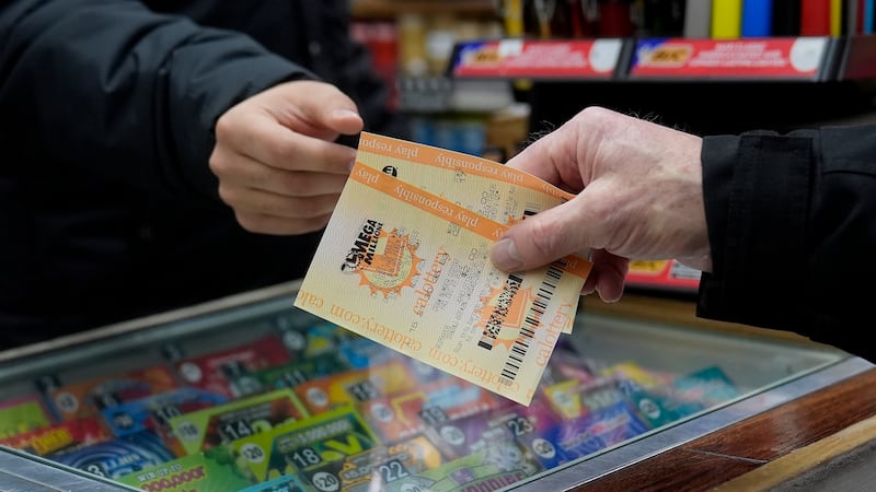 FILE - A customer buys a Mega Millions ticket at Rossi's Deli in San Francisco, Thursday, Dec....