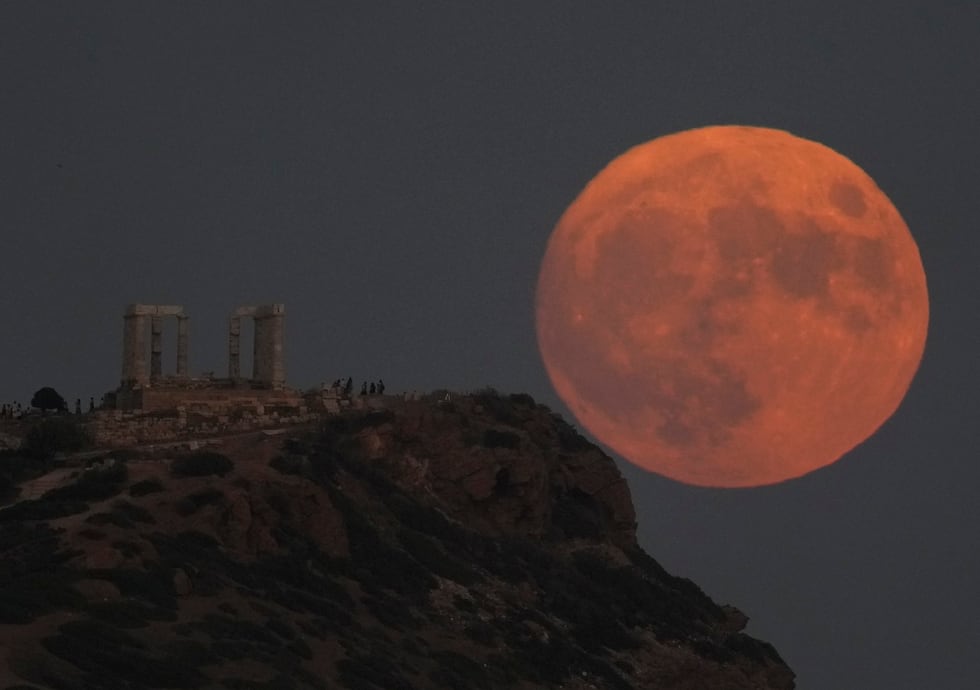 La superluna detrás del templo antiguo de Poseidón, a unos 70 kilómetros (45 millas) al sur de...