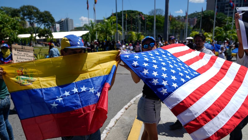 Demonstrators hold a Venezuelan and U.S. national flags during a student-led march calling for...