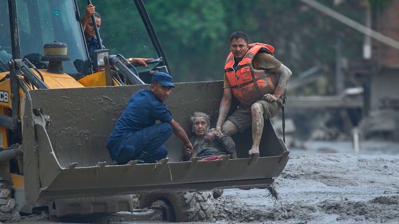 Rescatistas usan una excavadora para poner a salvo a las víctimas de una inundación a lo largo...