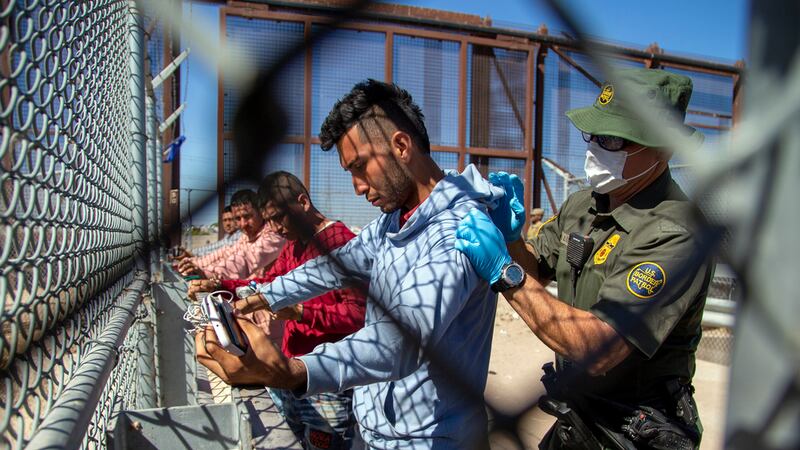 Migrantes son cacheados por un agente de la Patrulla Fronteriza al entrar a El Paso, Texas,...