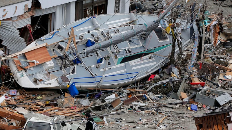 ARCHIVO-Un hombre pasa junto a un yate varado en una zona azotada por un tsunami en Ofunato,...