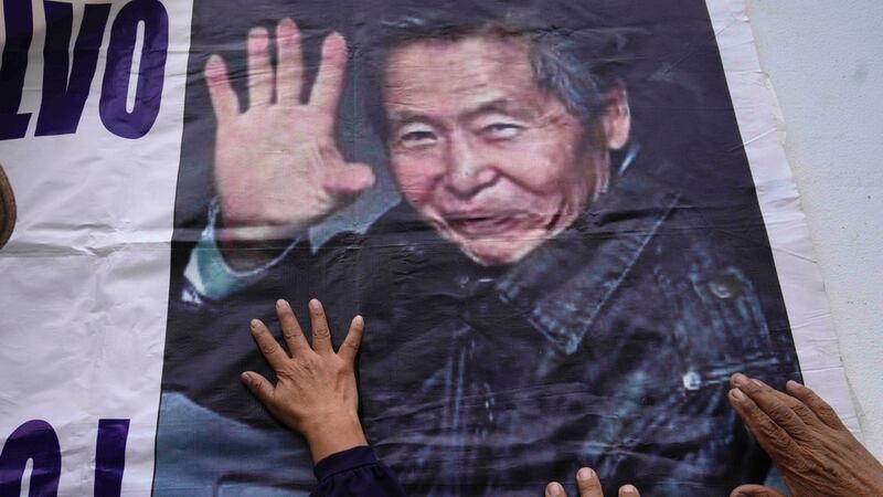 Los partidarios del expresidente encarcelado Alberto Fujimori tocan un cartel con su foto,...