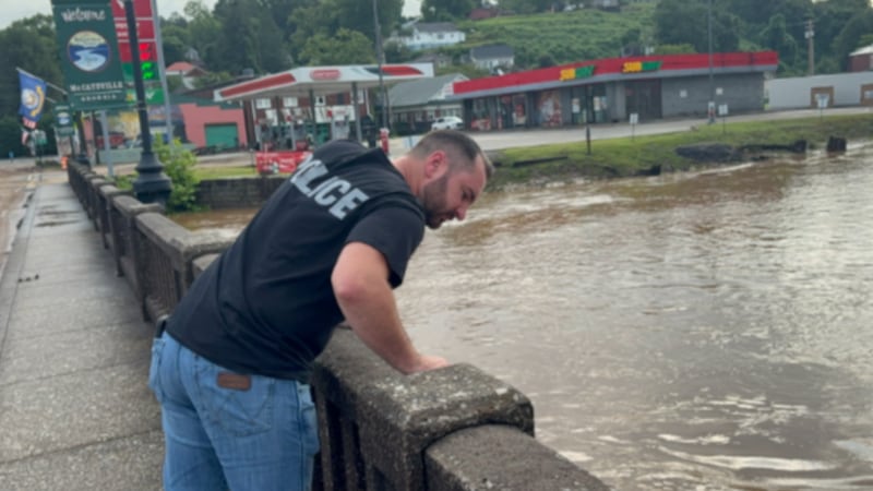 A police officer surveys the water level in McCaysville on Sunday after severe overnight...
