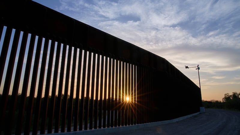 El sol se oculta detrás de un tramo del muro fronterizo, el 18 de junio de 2025, en Mission,...