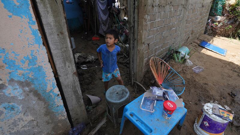 Un niño, en la entrada de su casa, dañada por el paso del devastador huracán Otis por la...