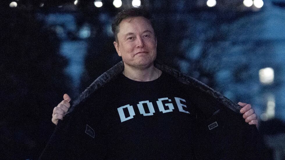 ARCHIVO - Elon Musk muestra una camiseta con las letras "DOGE" a los medios mientras camina...